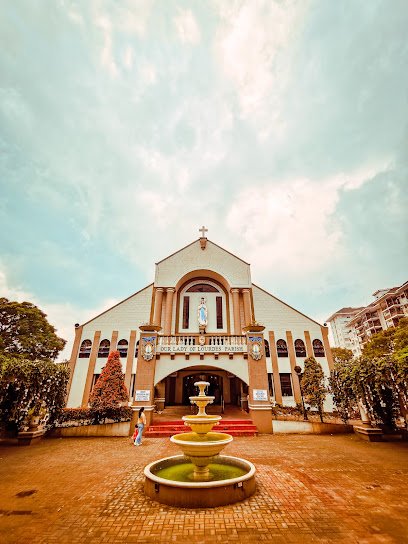 Our Lady of Lourdes Parish, a white church with a fountain in its courtyard